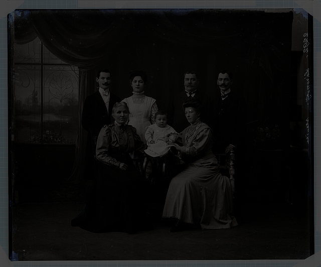Ateliérové foto - 7 členů rodiny (1 sedící batole, 2 ženy sedící, 1 žena stojící, 3 muži s kníry, stojící)  Na krabičce:  640 v kroužku, 532 skupiny (plíseň, prasklé) 22ks-sklo Na reverzu:... skupina