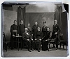 ateliér foto - muž a žena sedící mez nimi sedící kněz (ml Muž), vzadu stojící 2 ženy, 1 muž a 3 kněží